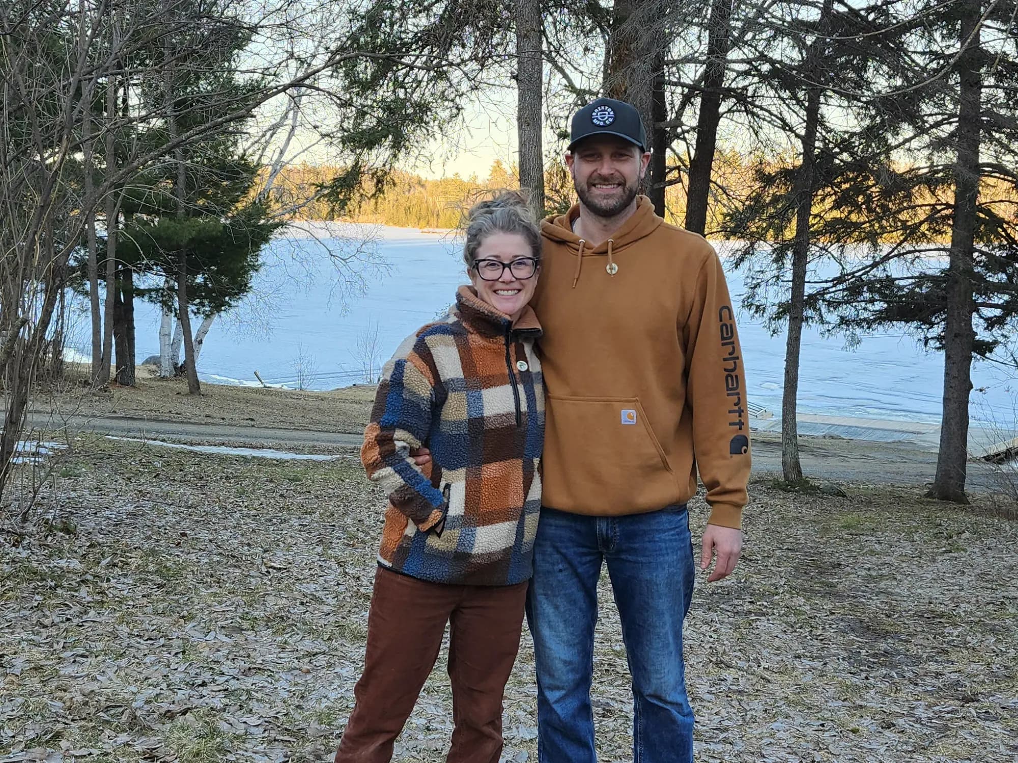 Corey and Keri, owners of Pipestone Lodge, standing together by the lake